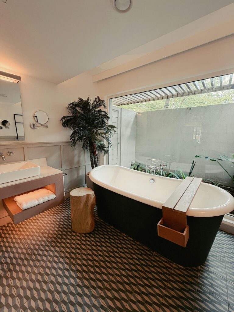 Chic bathroom with freestanding tub, large window, and geometric tiles.
